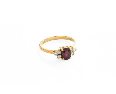 A Ruby and Diamond Ring, the oval cut ruby flanked by trios of round brilliant cut diamonds, in yellow claw settings, to a ta