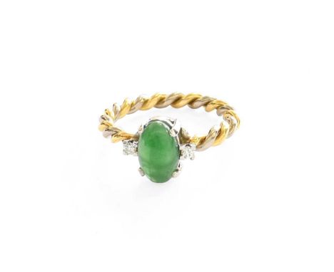 An 18 Carat Two Colour Gold Jade and Diamond Ring, the oval cabochon jade flanked by two round brilliant cut diamonds, in whi