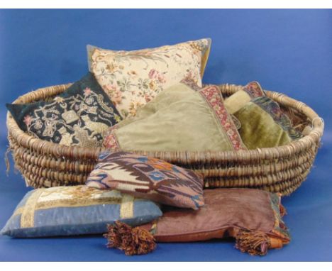 Large coracle shaped woven basket containing nine cushions, including a set of five vintage cushions with tapestry and velvet