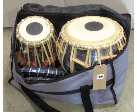 Two Tabla drums of varying size with hide strap work and stamped JAS complete with bina ring stands, housed within a canvas b