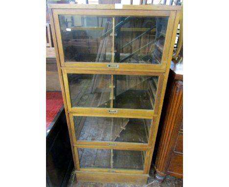 A vintage four tier haberdashery cabinet with glazed up and over doors, each section enclosing six open slides, each containi