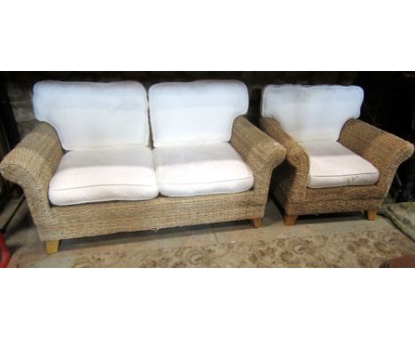 A contemporary rattan two seat sofa and matching armchair, with swept supports, upholstered loose cushions, raised on beechwo