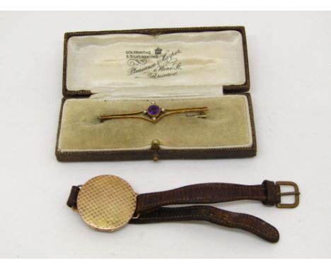 Unusual engine turned yellow metal locket upon a leather watch strap, with inscription to interior, together with a 15ct Edwa