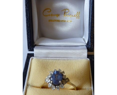 A ladies 9 carat yellow gold Dress Ring the central light blue hand cut oval stone surrounded by further smaller white stones