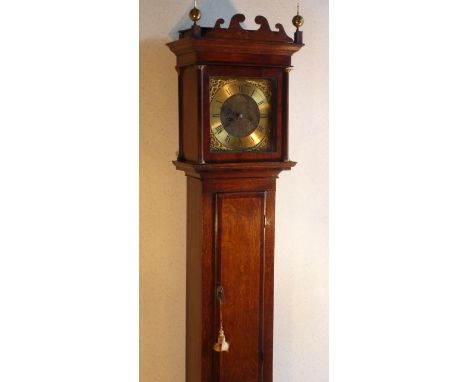 A George III period oak cased eight day Longcase Clock, the wavy style pediment flanked by two brass urn finials and above an