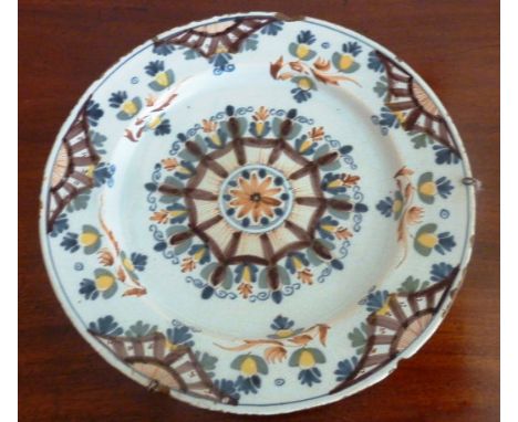 A large 18th Century Delftware Charger, hand decorated with a central stylised flower head surrounded by various further peta