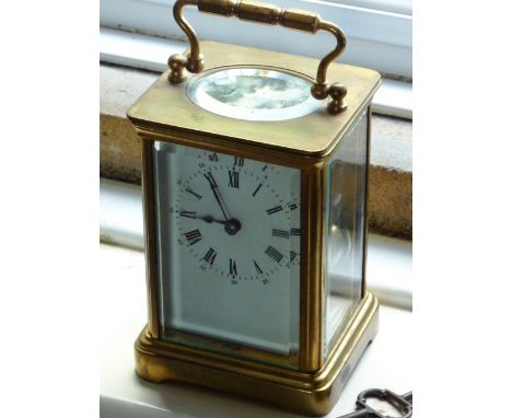An early 20th Century brass and glass sided Carriage Clock, white enamel dial with Roman numerals, the gilded movement striki