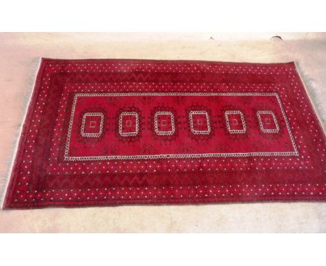 A hand knotted Eastern Carpet, central rectangle with six further rectangle motifs within a three border surround against a r