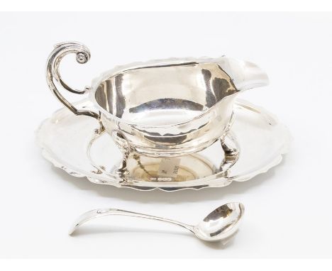 A Georgian style silver sauceboat, stand and ladle, the sauce boat and stand with wavy rim, the sauce boat on three hoof feet