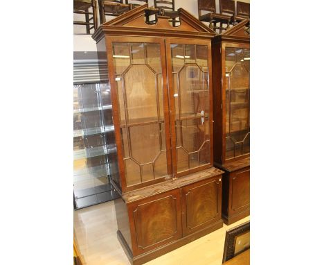 A pair of George III style mahogany bookcases, in the manner of Thomas Chippendale, each bookcase with a broken pediment, two