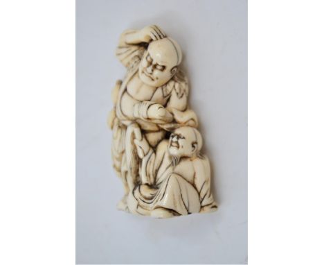 A Japanese ivory netsuke, Meiji period, modelled as a deity standing with seated attendant, 6cm (foot chipped).