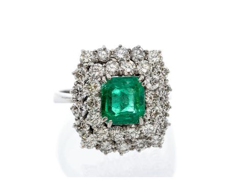 An emerald and diamond 18ct white gold cluster ring, comprising an emerald cut emerald set to the centre with a weight of app