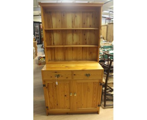 A contemporary solid pine dresser and rack, made by Hamlet, Bristol, the upper rack section fitted with two shelves and a bas