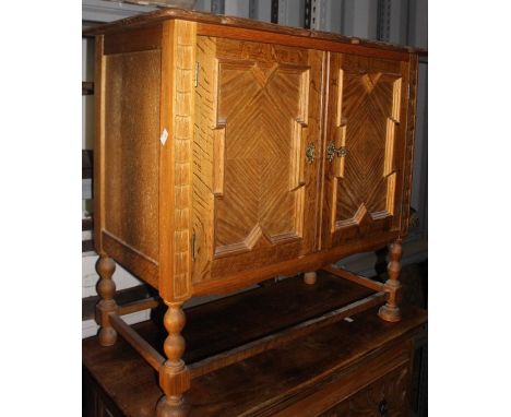 A George V Carolean Revival oak side cabinet, circa 1930, fitted with two panelled doors, with geometrically applied moulding