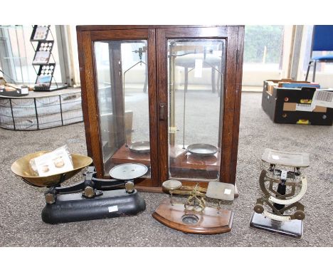 A collection of scales, comprising a set of postage scales in glass case, a bilateral set of postage scales with wooden plint