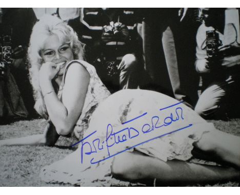BARDOT BRIGITTE: (1934-     ) French Actress and Sex Symbol. Signed 14 x 11 photograph of BB lying outdoors in a playful full