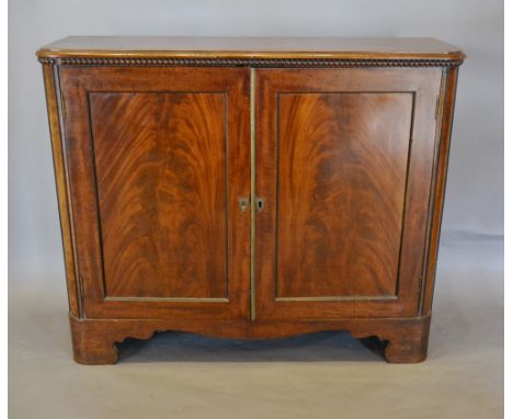 A Regency Mahogany Side Cabinet, the moulded beaded top above two panelled doors raised upon bracket feet with shaped frieze,