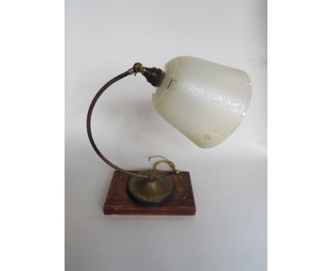 An angled desk lamp on wood block base with a frosted glass shade 