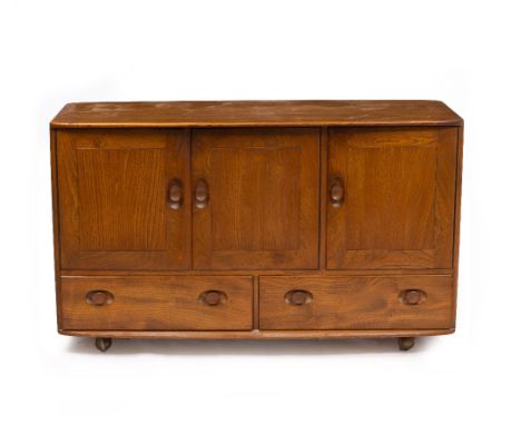 AN ERCOL LIGHT ELM SIDEBOARD with three panelled doors above two drawers, raised on easyroll casters, 129.5cm wide x 49.5cm d