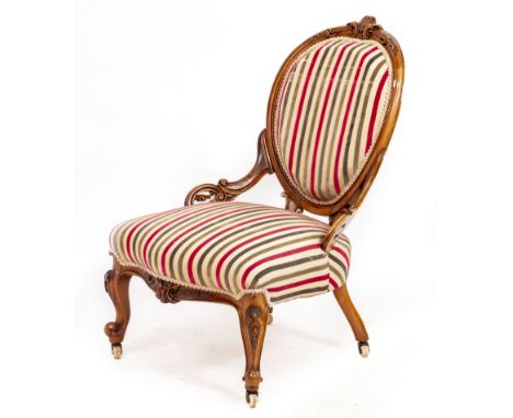 A VICTORIAN WALNUT LOW OCCASIONAL CHAIRwith overstuffed upholstered back and serpentine fronted seat, carved decoration to th
