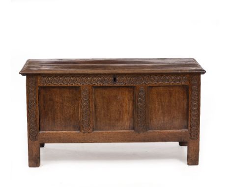 AN 18TH CENTURY OAK COFFER with panelled sides and carved geometric decoration, raised on stile feet, 115cm wide x 50cm deep 