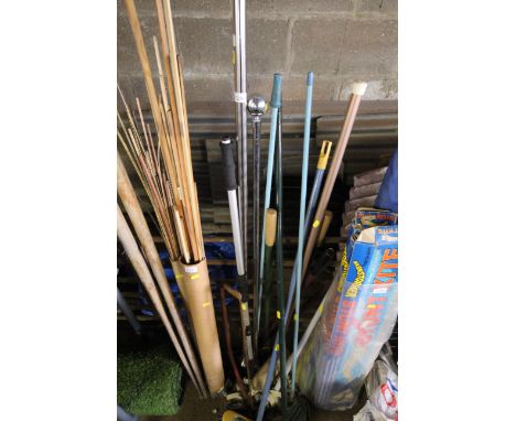 A quantity of long handled gardening tools to include brushes, bow saw, mops, two chrome curtain poles etc