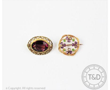 An Edwardian amethyst and demantoid garnet set brooch, designed as a sinuous circular brooch with amethyst set shamrocks inte