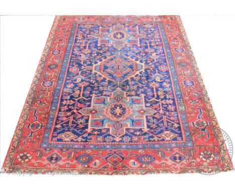 A Caucasian wool carpet, worked with geometric motifs against a blue ground, 184cm x 141cm