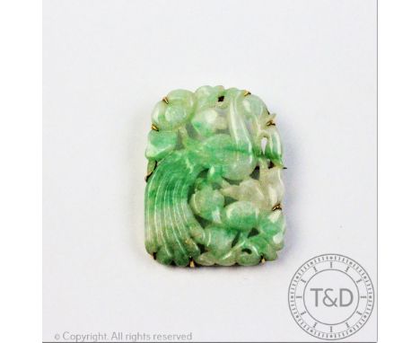 A carved jade plaque within brooch setting, the panel carved depicting a peacock perched amongst branches, within yellow meta