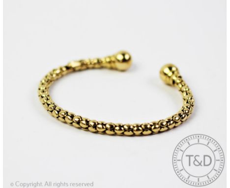 A 9ct yellow gold torque style bangle, with circular disc finish, applied pad stamped '375', metal core (at fault)  CONDITION