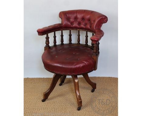 An Edwardian walnut swivel desk chair, with button back, arms and seat with later leatherette upholstery, on four legs, 83cm 