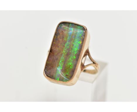 A 9CT GOLD BOULDER OPAL RING, of a rectangular form bolder opal displaying flashes of green, blue, yellow and small amounts o