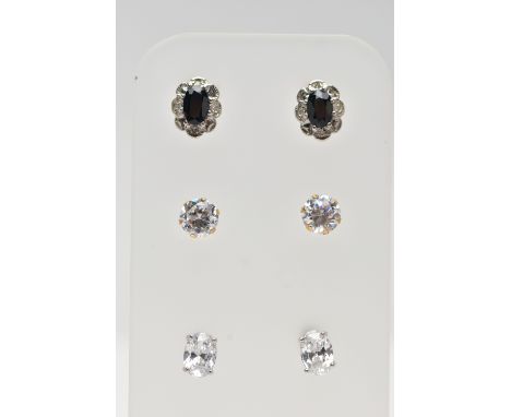 THREE PAIRS OF GEM SET EARRINGS, the first a pair of cluster stud earrings, set with an oval cut blue sapphire within a surro