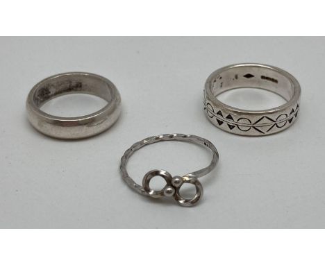 3 modern design silver rings. A plain band, a band with diamond and circle decoration and a twisted silver band with bow deta
