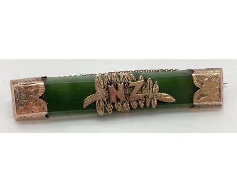 An antique nephrite jade and gold New Zealand bar brooch with pin back and safety chain. Gold casing to each end with engrave