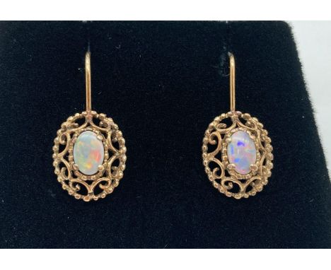 A pair of 9ct gold and opal drop earrings with hook wires. Central oval opal (approx. 6mm x 4mm) in a decorative pierced work