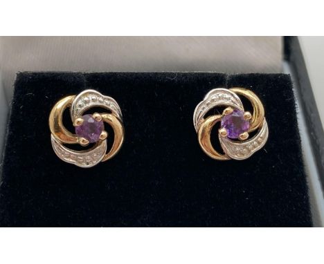 A pair of 9ct gold swirl design stud earrings set with central amethyst stones. Complete with butterfly backs. Marked 375 to 