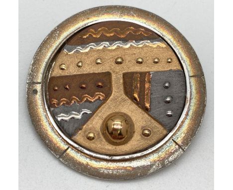 A modern abstract design brooch in metallic tones. Central circular ceramic plaque is mounted in a silver gilt mount with ful