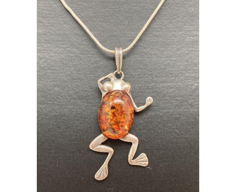 A silver frog shaped pendant set with an oval cognac amber cabochon, on a 15 inch fine snake chain with lobster clasp. Pendan