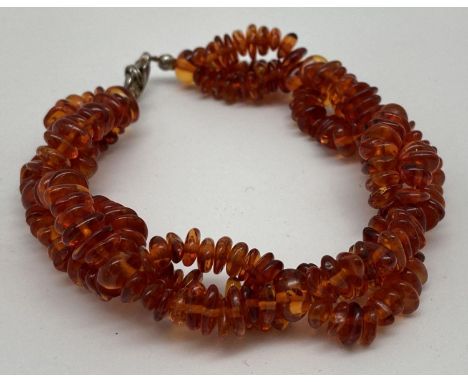 A modern triple strand plaited design cognac amber chip bracelet with lobster style clasp. Total length approx. 8 inches. 