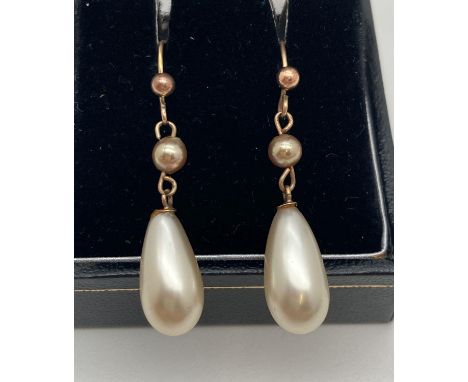 A pair of 9ct gold and faux pearl drop earrings. Cream coloured drop pearls approx. 1.5cm long linked to a small round coffee