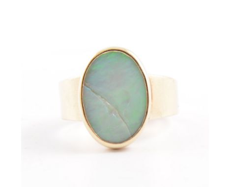 An opal dress ring, the oval cabochon cut stone, 14mm x 9mm, collet set in a 9 carat yellow gold mount with wide shank and sh