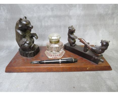 AN EARLY 20TH CENTURY BLACK FOREST STYLE INKSTAND, modelled with a seated bear, central heavy glass inkwell and two smaller b
