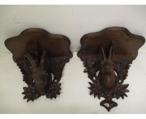 A pair of late 19th century German Black Forest wall brackets, each with a serpentine shelf over a goats head and leaf back, 