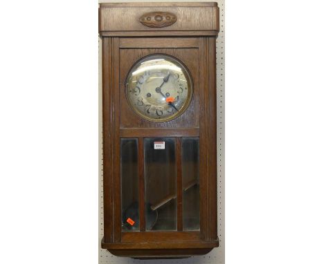 A 1920s oak drop trunk wall clock, with pendulum
