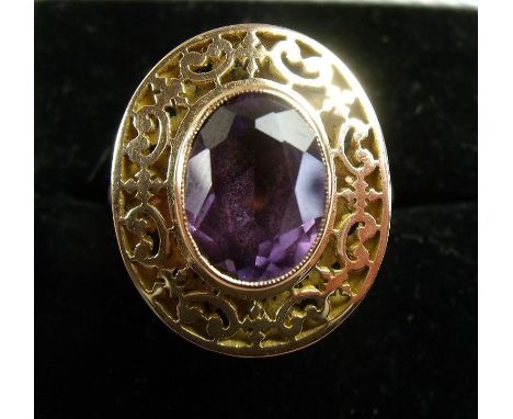 A 14 carat gold ring set amethyst in pierced scrollwork surround 
