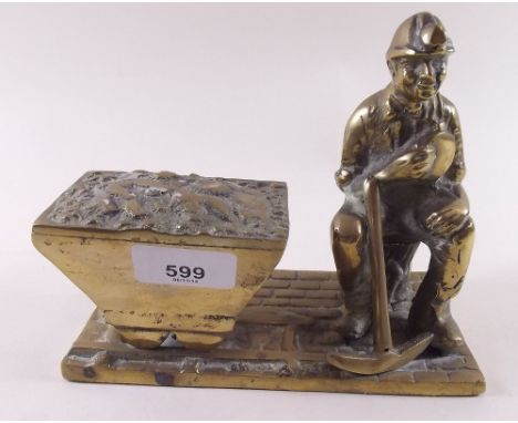 A large and heavy brass doorstop figure of a miner with pick axe and coal truck 
