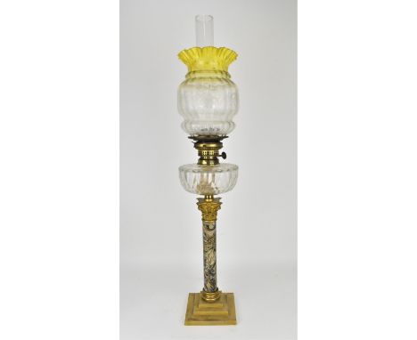 A Victorian oil lamp, with clear faceted reservoir and floral etched shade with yellow frill rim, on a marbled effect column 