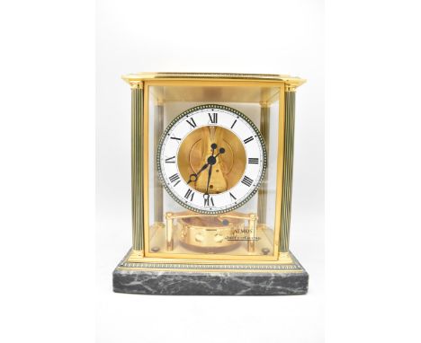 A Jaeger LeCoultre Atmos clock, the glass and brass case with green enamel highlights and corner columns, enclosing the gilt 