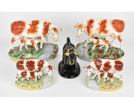 A pair of Victorian Staffordshire ceramic cows with calves, on natutalistic bases, together with a similar smaller pair, and 